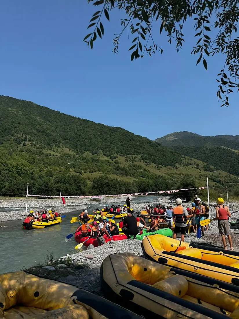 Rafts lined up on the riverbank under the trees