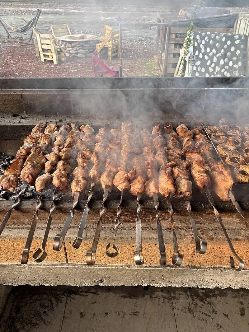 Mtsvadi skewers grilling over coals at the rafting camp